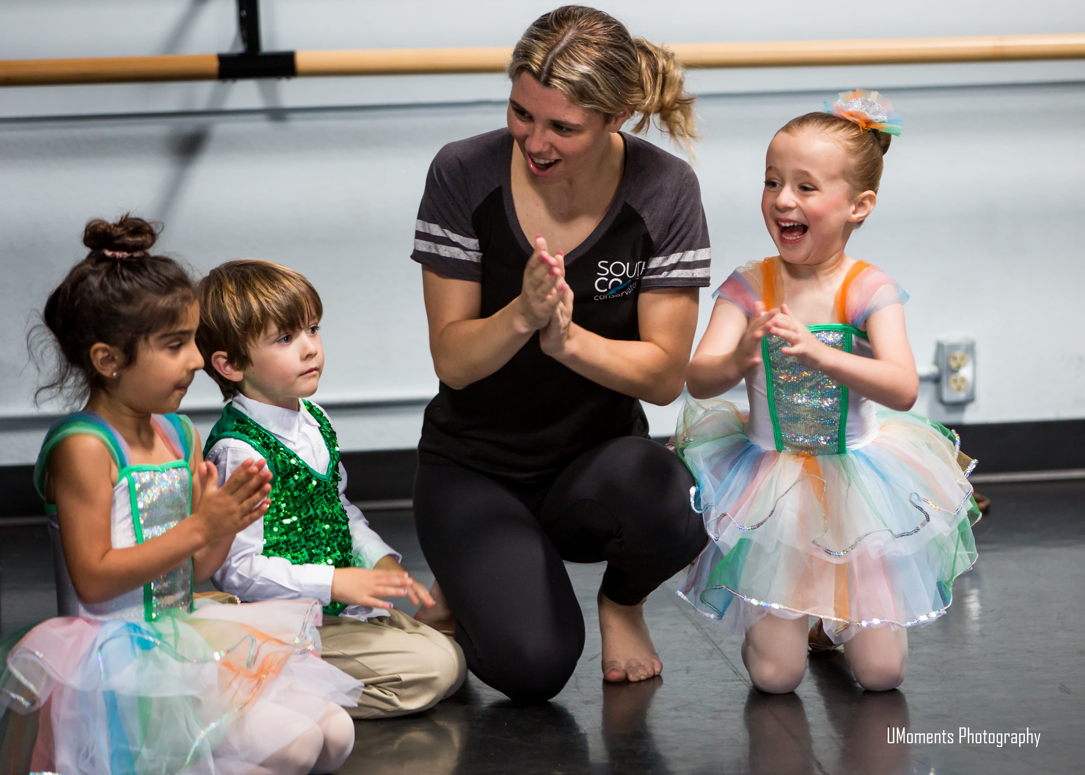 Teacher smiling with young dancers in recital costumes
